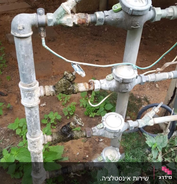 צינורות מים עם ברזים ומדי מים בחוץ